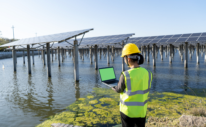 Back view of female engineer using laptop at solar power plant